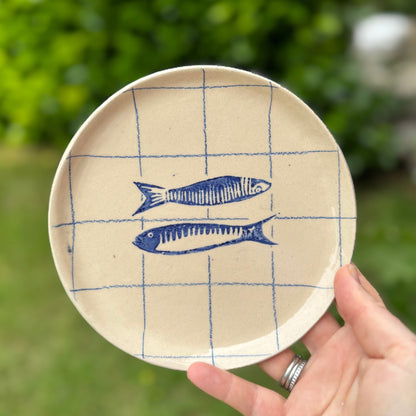 Handmade ceramic sardine pair plate with cobalt blue grid design held outdoors