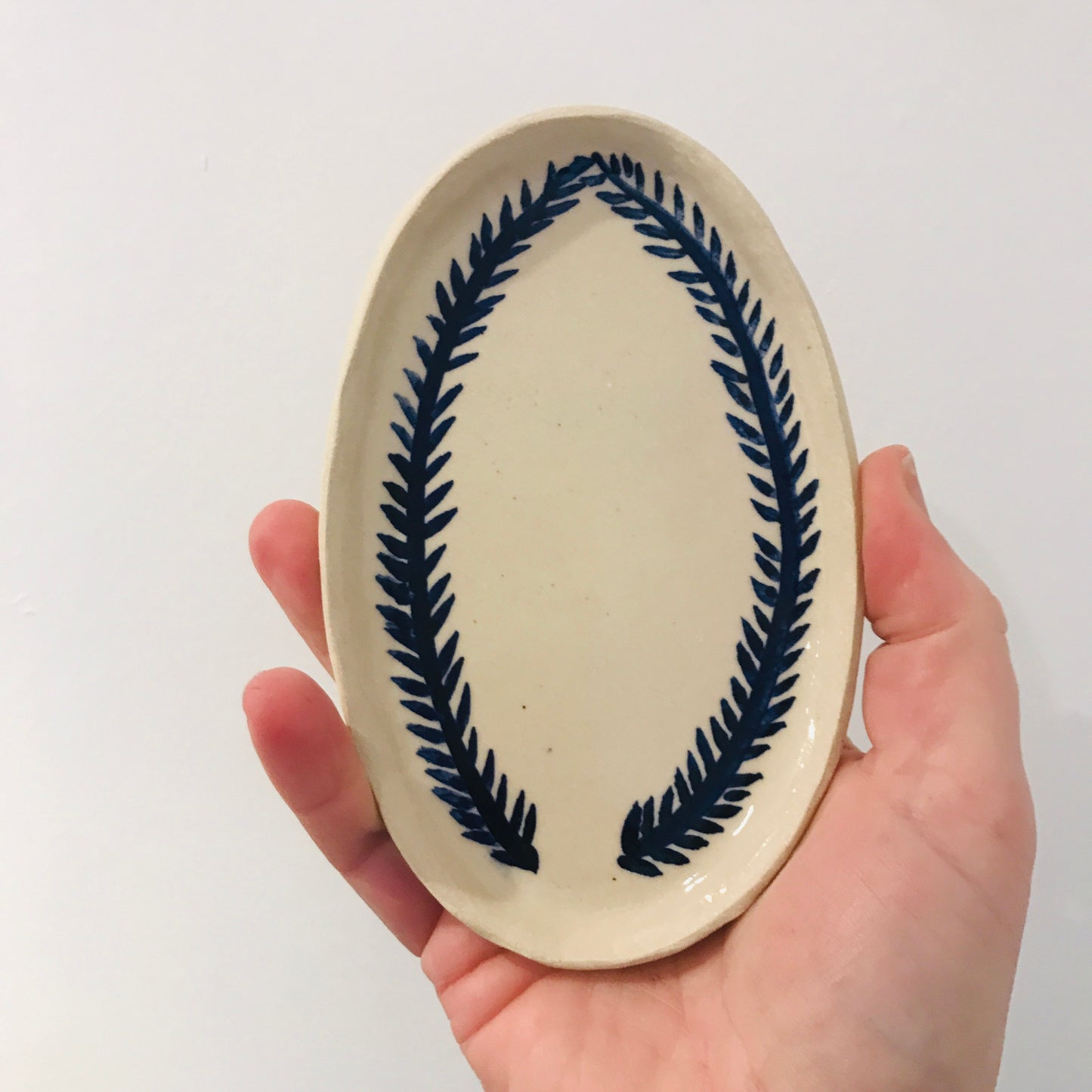 Natural stoneware glazed ceramic oval side plate with hand painted blue leaf garland floral design