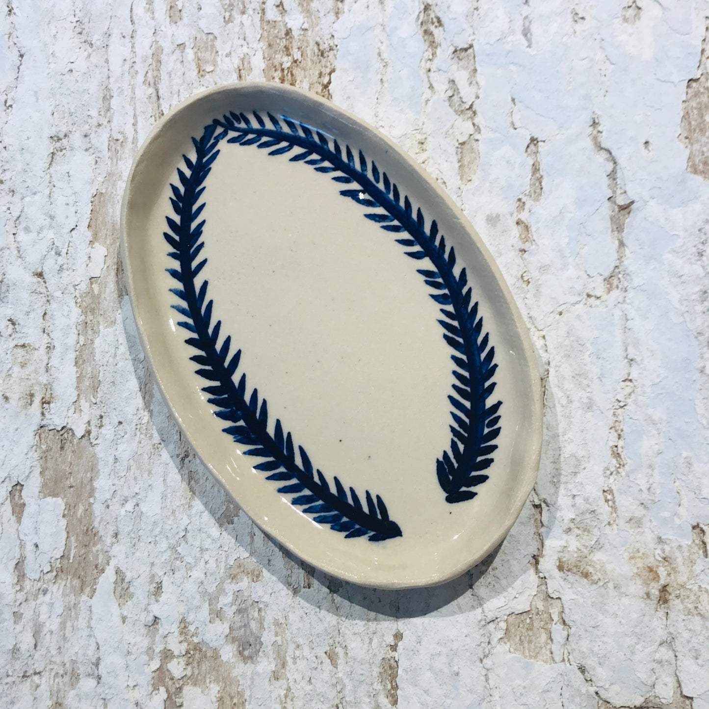 Natural stoneware glazed ceramic oval side plate with hand painted blue leaf garland floral design