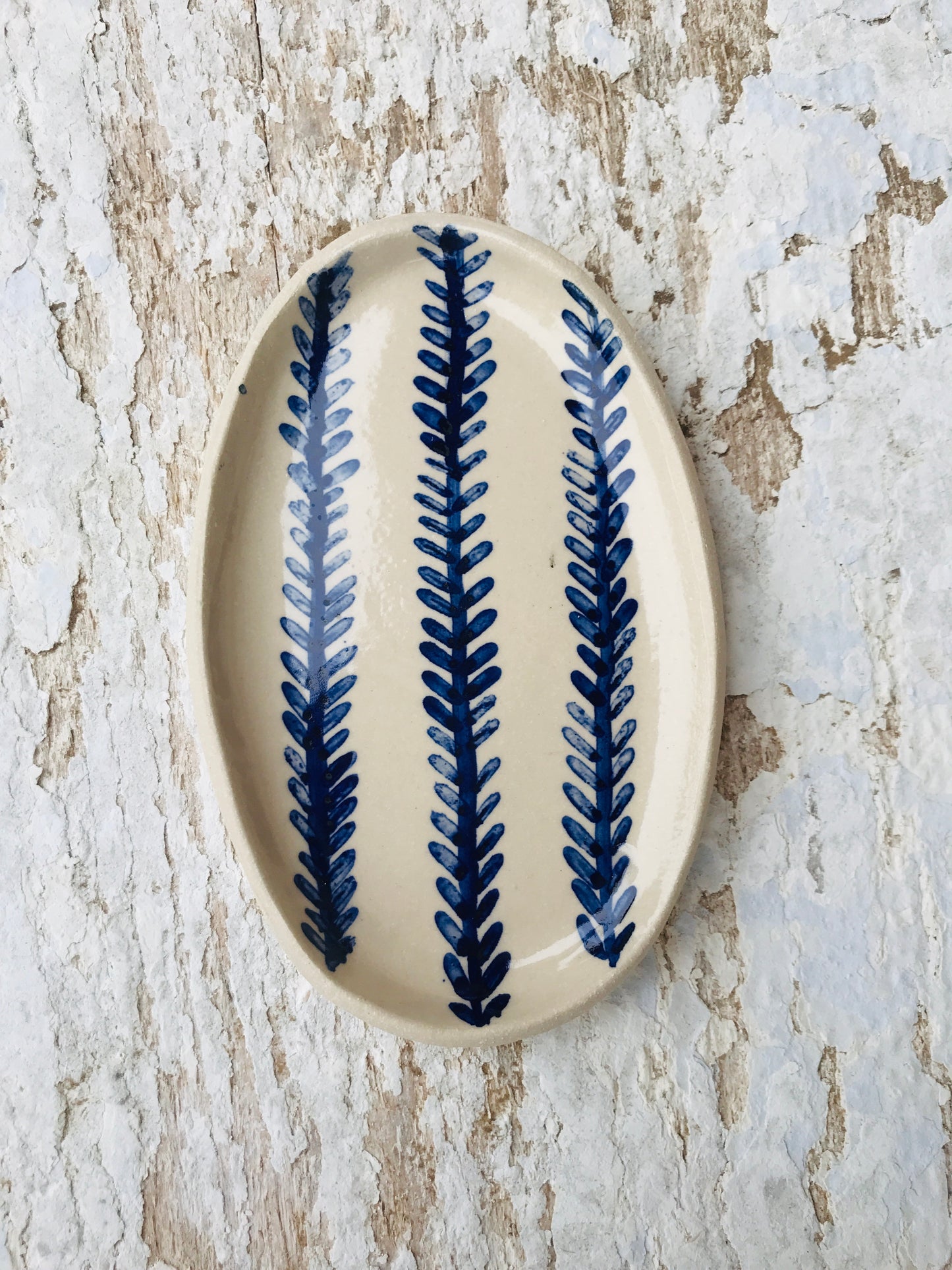 Natural stoneware glazed ceramic oval side plate with hand painted blue leaf garland floral design